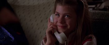 Movie still from “The Negotiator” (1998), directed by F. Gary Gray – A young girl is smiling while talking on a phone; Close Up shot, Low angle