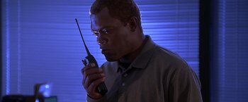 Movie still from “The Negotiator” (1998), directed by F. Gary Gray – A man is holding a walkie talkie in his hand; Close Up shot, Low angle