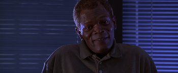 Movie still from “The Negotiator” (1998), directed by F. Gary Gray – An older man smiling for the camera in front of a window; Close Up shot, Low angle