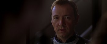 Movie still from “The Negotiator” (1998), directed by F. Gary Gray – A man with a beard is looking at the camera; Close Up shot, Over the shoulder angle