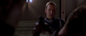 Movie still from “The Negotiator” (1998), directed by F. Gary Gray – A man in a police uniform is holding a gun; Close Up shot, Over the shoulder angle