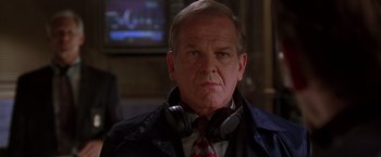 Movie still from “The Negotiator” (1998), directed by F. Gary Gray – An older man wearing headphones and a red tie; Close Up shot, Over the shoulder angle