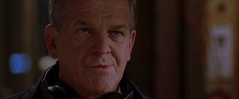 Movie still from “The Negotiator” (1998), directed by F. Gary Gray – An older man wearing a blue jacket and a black tie; Close Up shot, Over the shoulder angle