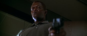 Movie still from “The Negotiator” (1998), directed by F. Gary Gray – A man holding a gun while standing in front of a mirror; Close Up shot, Low angle