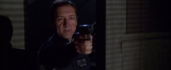 Movie still from “The Negotiator” (1998), directed by F. Gary Gray – A man holding a gun in his right hand while wearing a police uniform; Close Up shot, Low angle