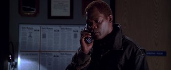 Movie still from “The Negotiator” (1998), directed by F. Gary Gray – A man talking on a cell phone in a dark room; Close Up shot, Low angle