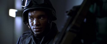 Movie still from “The Negotiator” (1998), directed by F. Gary Gray – A man wearing a helmet and holding a rifle; Close Up shot, Over the shoulder angle