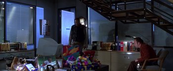 Movie still from “The Negotiator” (1998), directed by F. Gary Gray – A man standing next to a pile of presents; Wide shot, Over the shoulder angle