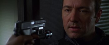 Movie still from “The Negotiator” (1998), directed by F. Gary Gray – A person holding a gun; Close Up shot, Over the shoulder angle
