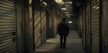 Movie still from “Guillermo del Toro's Cabinet of Curiosities” (2022), directed by Keith Thomas – A man walking down a hallway in a building; Wide shot, High angle
