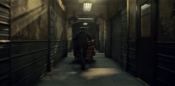 Movie still from “Guillermo del Toro's Cabinet of Curiosities” (2022), directed by Keith Thomas – A man pushing a cart down a dark hallway; Wide shot, High angle