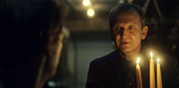 Movie still from “Guillermo del Toro's Cabinet of Curiosities” (2022), directed by Keith Thomas – An older man in a black suit looking at the camera; Close Up shot, Over the shoulder angle