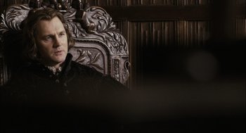 Movie still from “The Other Boleyn Girl” (2008), directed by Justin Chadwick – A person sitting in a chair in front of a wooden wall; Close Up shot, Over the shoulder angle