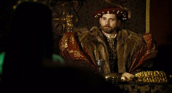 Movie still from “The Other Boleyn Girl” (2008), directed by Justin Chadwick – A man sitting in a chair with a glass of wine; Medium shot, Over the shoulder angle
