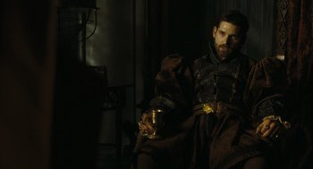 Movie still from “The Other Boleyn Girl” (2008), directed by Justin Chadwick – A man sitting in a chair holding a cup; Medium shot, Over the shoulder angle