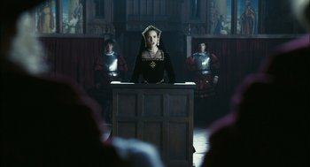 Movie still from “The Other Boleyn Girl” (2008), directed by Justin Chadwick – A woman standing at a table in front of a group of men; Medium shot, Over the shoulder angle