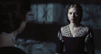Movie still from “The Other Boleyn Girl” (2008), directed by Justin Chadwick – A woman in a black and white dress standing next to a brick wall; Medium shot, Over the shoulder angle