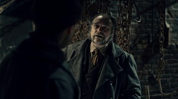 Movie still from “Guillermo del Toro's Cabinet of Curiosities” (2022), directed by Keith Thomas – An older man in a coat and tie talking to a younger man; Medium shot, Over the shoulder angle