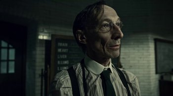 Movie still from “Guillermo del Toro's Cabinet of Curiosities” (2022), directed by Keith Thomas – An older man wearing glasses and a striped shirt; Close Up shot, Low angle