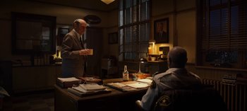 Movie still from “Guillermo del Toro's Cabinet of Curiosities” (2022), directed by Keith Thomas – Two men are sitting at a desk in a room; Wide shot, Over the shoulder angle