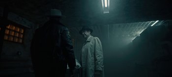 Movie still from “Guillermo del Toro's Cabinet of Curiosities” (2022), directed by Keith Thomas – A man wearing a hat and a trench coat standing next to another man; Medium shot, Over the shoulder angle