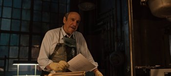 Movie still from “Guillermo del Toro's Cabinet of Curiosities” (2022), directed by Keith Thomas – An older man wearing gloves and holding papers; Medium shot, Low angle