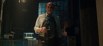 Movie still from “Guillermo del Toro's Cabinet of Curiosities” (2022), directed by Keith Thomas – An older man wearing an apron holding a wine glass; Medium shot, Low angle