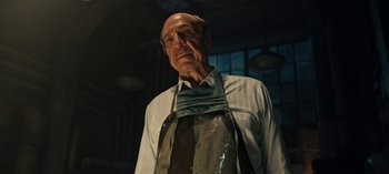 Movie still from “Guillermo del Toro's Cabinet of Curiosities” (2022), directed by Keith Thomas – An older man wearing an apron in a dimly - lit room; Close Up shot, Low angle