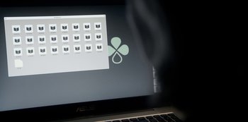 Movie still from “The Rain” (2018), created by Jannik Tai Mosholt – A computer screen with a shamrock on it; Extreme Close Up shot, Overhead angle
