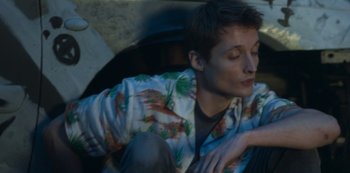 Movie still from “The Rain” (2018), created by Jannik Tai Mosholt – A man sitting in a car with his head resting on his arm; Close Up shot, High angle