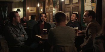 Movie still from “The Ritual” (2017), directed by David Bruckner – A group of people sitting at a table in a pub; Wide shot, Over the shoulder angle