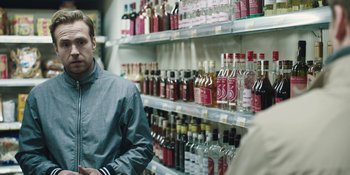 Movie still from “The Ritual” (2017), directed by David Bruckner – A man is standing in front of a shelf filled with bottles; Close Up shot, Over the shoulder angle