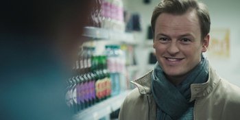 Movie still from “The Ritual” (2017), directed by David Bruckner – A man with a scarf and a jacket in a store; Close Up shot, Over the shoulder angle