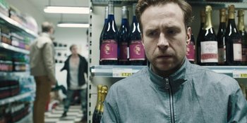 Movie still from “The Ritual” (2017), directed by David Bruckner – A man standing in front of a wine shelf; Close Up shot, Over the shoulder angle
