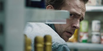 Movie still from “The Ritual” (2017), directed by David Bruckner – A person looking at something on a table; Close Up shot, Over the shoulder angle