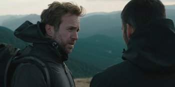 Movie still from “The Ritual” (2017), directed by David Bruckner – Two men standing on top of a hill talking to each other; Close Up shot, Over the shoulder angle