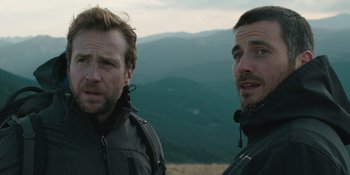 Movie still from “The Ritual” (2017), directed by David Bruckner – A couple of men standing on top of a hill; Close Up shot, Low angle