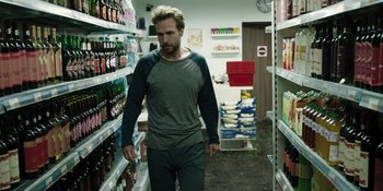 Movie still from “The Ritual” (2017), directed by David Bruckner – A man walking through a store filled with shelves of beverages; Medium shot, Over the shoulder angle