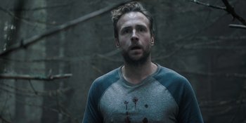 Movie still from “The Ritual” (2017), directed by David Bruckner – A man in a grey shirt is looking at the camera; Close Up shot, Over the shoulder angle