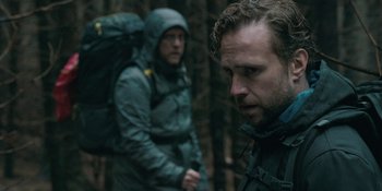 Movie still from “The Ritual” (2017), directed by David Bruckner – Two men in rain gear are standing in the woods; Close Up shot, Over the shoulder angle