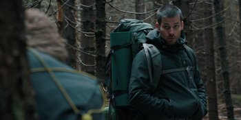 Movie still from “The Ritual” (2017), directed by David Bruckner – A man with a backpack in the woods; Medium shot, Over the shoulder angle