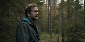 Movie still from “The Ritual” (2017), directed by David Bruckner – A man standing in the middle of a forest looking to his left; Medium shot, Over the shoulder angle
