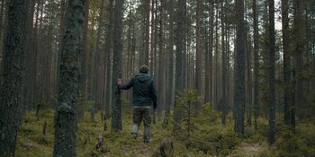 Movie still from “The Ritual” (2017), directed by David Bruckner – A man standing in the middle of a forest; Wide shot, Low angle