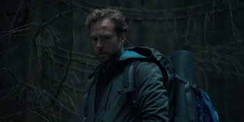 Movie still from “The Ritual” (2017), directed by David Bruckner – A man with a backpack is standing in the woods; Close Up shot, Low angle