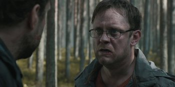 Movie still from “The Ritual” (2017), directed by David Bruckner – A person wearing glasses near a forest; Close Up shot, Over the shoulder angle