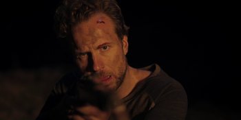 Movie still from “The Ritual” (2017), directed by David Bruckner – A person holding a gun in a dark room; Close Up shot, Over the shoulder angle