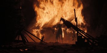 Movie still from “The Ritual” (2017), directed by David Bruckner – A man standing in front of a burning house; Extreme Wide shot, Low angle