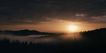 Movie still from “The Ritual” (2017), directed by David Bruckner – The sun is setting over a valley filled with trees; Extreme Wide shot, Low angle