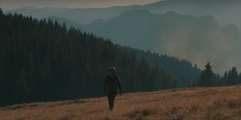 Movie still from “The Ritual” (2017), directed by David Bruckner – A man walking through a field of tall brown grass; Extreme Wide shot, Low angle