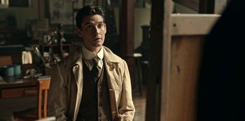 Movie still from “Guillermo del Toro's Cabinet of Curiosities” (2022), directed by Keith Thomas – A man wearing a suit and tie standing in a room; Medium shot, Over the shoulder angle